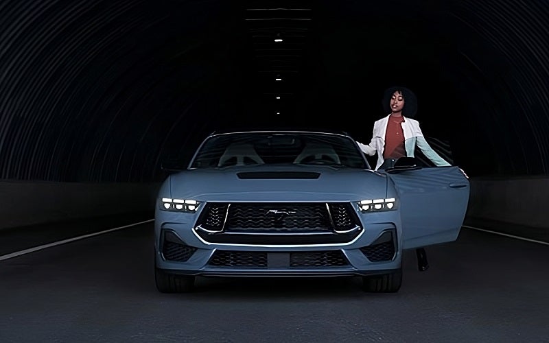 Ford Mustang parked in warehouse with woman standing next to it